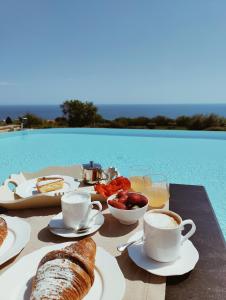 uma mesa com comida de pequeno-almoço e café numa mesa junto a uma piscina em Pamperduto Country Resort em Porto Potenza Picena