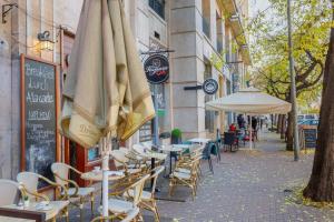 an outdoor cafe with tables and umbrellas on a street at Gorgeous & Super Central Studio in Budapest