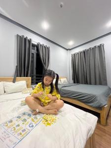 a young girl sitting on a bed in a bedroom at Nomad Stay in Phan Rang