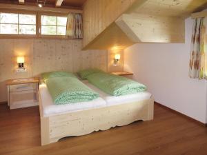 uma cama num quarto com duas almofadas verdes em Apartment Nachbarbauer - LFE120 by Interhome em Lofer