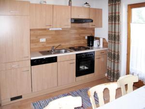 een keuken met houten kasten en een wastafel bij Apartment Josef - ZAZ590 by Interhome in Aschau