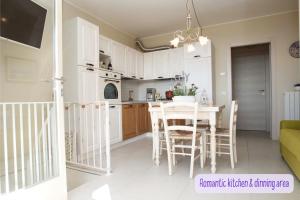 a kitchen with white cabinets and a table and chairs at Panorama lake view, pool & garden, 2 bathrooms, kingsize & single-beds, fast Internet in Toscolano Maderno