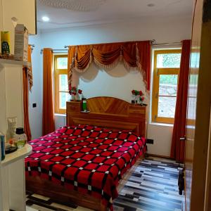 a bedroom with a bed with a red and black blanket at The Himalayan Inn homestay in Gulmarg