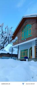 a house with snow in front of it at The Himalayan Inn homestay in Gulmarg