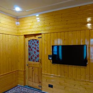 a flat screen tv hanging on a wooden wall at The Himalayan Inn homestay in Gulmarg