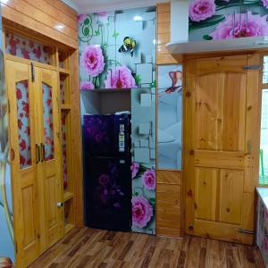 a kitchen with a refrigerator and flowers on the wall at The Himalayan Inn homestay in Gulmarg