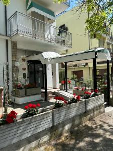 a building with a patio with red flowers and an awning at Camere Capinera in Cesenatico