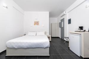 a bedroom with a white bed and a kitchen at Pancratium Villas & Suites in Akrotiri