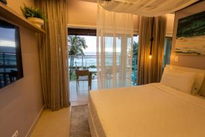 a bedroom with a bed and a view of the ocean at Amora Hotel Maresias in Maresias