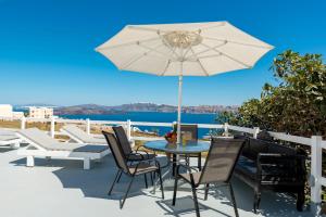 eine Terrasse mit einem Tisch, Stühlen und einem Sonnenschirm in der Unterkunft Pancratium Villas & Suites in Akrotiri