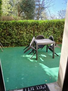 a table and chairs sitting on a green patio at Gites en Cevennes "Chez Steloune" in Génolhac