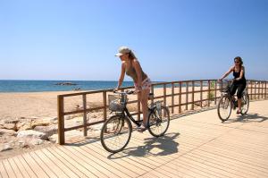 two women riding bikes on a boardwalk at the beach at Villa Dorada in Montroig