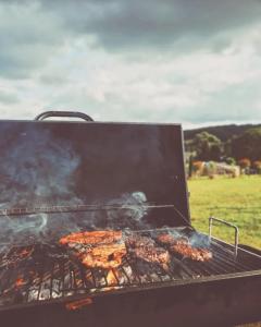 a grill with a bunch of food cooking on it at Greenacres Glamping in Lea