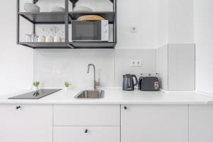 een witte keuken met een spoelbak en een magnetron bij Newly designed central studio in Boedapest