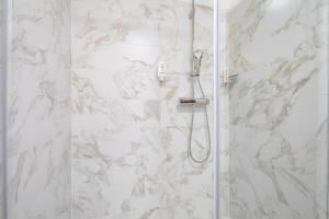 a bathroom with a shower with white marble walls at Perfect relax in Somlószőlős