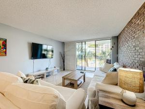 a living room with white furniture and a brick wall at Beach Front Condo In Paradise Marco Island in Marco Island