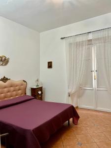 een slaapkamer met een bed met paarse lakens en een raam bij Casa del Duomo in Siracusa
