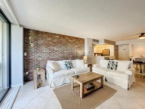 una sala de estar con 2 sofás y una pared de ladrillo en Beach Front Condo In Paradise Marco Island, en Marco Island