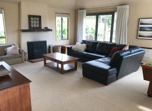 a living room with a black leather couch and a table at Sargood Splendour - Wanaka Holiday Home in Wanaka