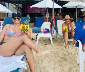 two women in bathing suits sitting on the beach at Hostal la Canoa in Playa Blanca