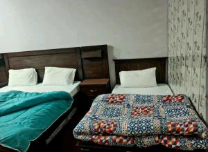 dos camas sentadas una al lado de la otra en una habitación en Al Sadiq Guest House, en Murree