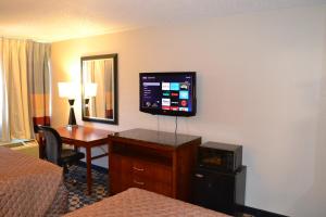 Habitación de hotel con escritorio y TV en la pared en Dayspring Extended Stay, en Greensboro