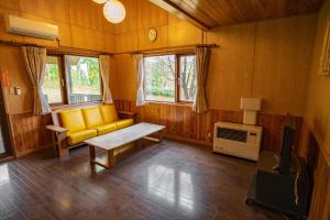 sala de estar con sofá amarillo y TV en Morinoyu Hotel Hanakagura en Asahikawa