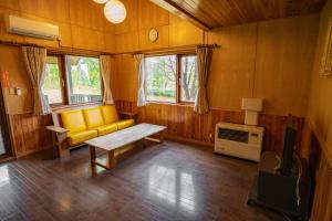 a living room with a yellow couch and a tv at Morinoyu Hotel Hanakagura in Asahikawa
