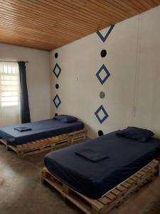 two twin beds in a room with a wall with at Hostel Nugeku in Rincón