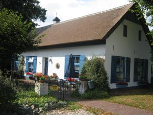 a white house with blue windows and a roof at Droomboerderijtje in Merselo