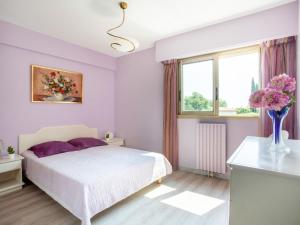 - une chambre avec un lit blanc et un vase de fleurs dans l'établissement Apartment Parc lautin by Interhome, à Cagnes-sur-Mer