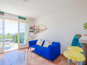 een woonkamer met een blauwe bank en een tafel bij Apartment Le Petit Village-1 by Interhome in Les Issambres