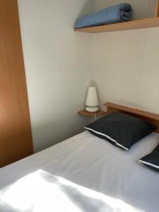 a bedroom with a bed with a blue pillow and a lamp at Mobilhome au coeur de la Camargue in Le Grau-du-Roi