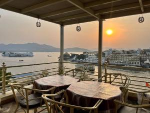 2 tafels en stoelen op een balkon met uitzicht op het water bij Hotel The Tiger in Udaipur