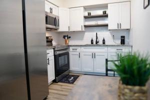 a kitchen with white cabinets and a stainless steel refrigerator at Jay's Cozy Arts in Tampa