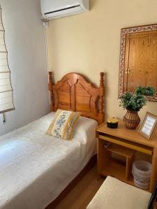 a bedroom with a bed with a wooden headboard and a table at Un Lugar Para Descansar En Alicante in Alicante