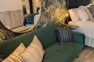 a green couch with pillows in a bedroom at Luxury Menlyn Maine Apartment in Pretoria