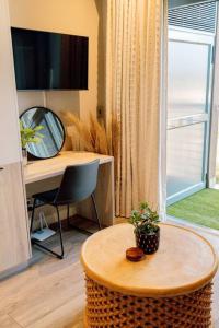 a living room with a table and a desk and a television at Luxury Menlyn Maine Apartment in Pretoria