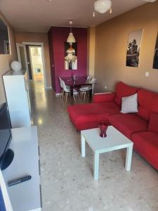 ein Wohnzimmer mit einem roten Sofa und einem Tisch in der Unterkunft Bonito apartamento tesorillo in Almuñécar