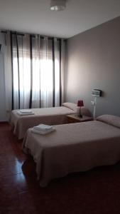 a hotel room with two beds and a window at HOTEL LAGO in Villanueva de Arosa