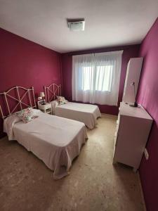 ein lila Zimmer mit zwei Betten und einem Fenster in der Unterkunft Bonito apartamento tesorillo in Almuñécar