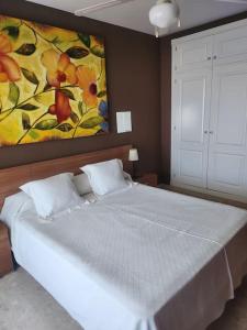 ein Schlafzimmer mit einem großen Bett mit einem Gemälde an der Wand in der Unterkunft Bonito apartamento tesorillo in Almuñécar + 21 Fotos