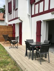einen schwarzen Tisch und Stühle auf einer Holzterrasse in der Unterkunft Maison de 2 chambres avec jardin clos et wifi a Briscous in Briscous