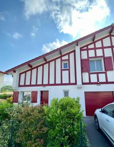 ein rotes und weißes Haus mit einem Auto vor dem Haus in der Unterkunft Maison de 2 chambres avec jardin clos et wifi a Briscous in Briscous