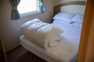 韋茅斯的住宿－Littlesea Caravan，卧室内的一张未铺好的床,设有窗户