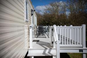 un porche de una casa con una barandilla blanca en Littlesea Caravan, en Weymouth