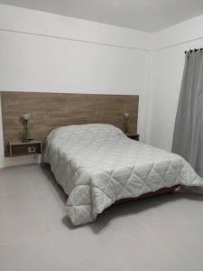 1 dormitorio blanco con 1 cama con cabecero de madera en Fortunati Departamentos en General Sarmiento