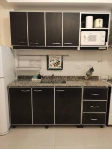 a kitchen with a sink and a microwave at Fortunati Departamentos in General Sarmiento +16 photos