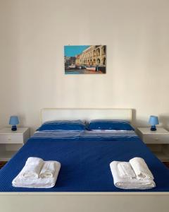 1 dormitorio con 1 cama azul y 2 toallas blancas en Marger Apartments, en Santa Maria di Castellabate