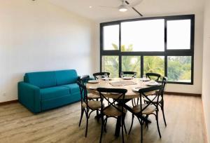 a dining room with a table and a blue couch at Grand Appartement Mer - Pétrel 1 in Trois Bassins